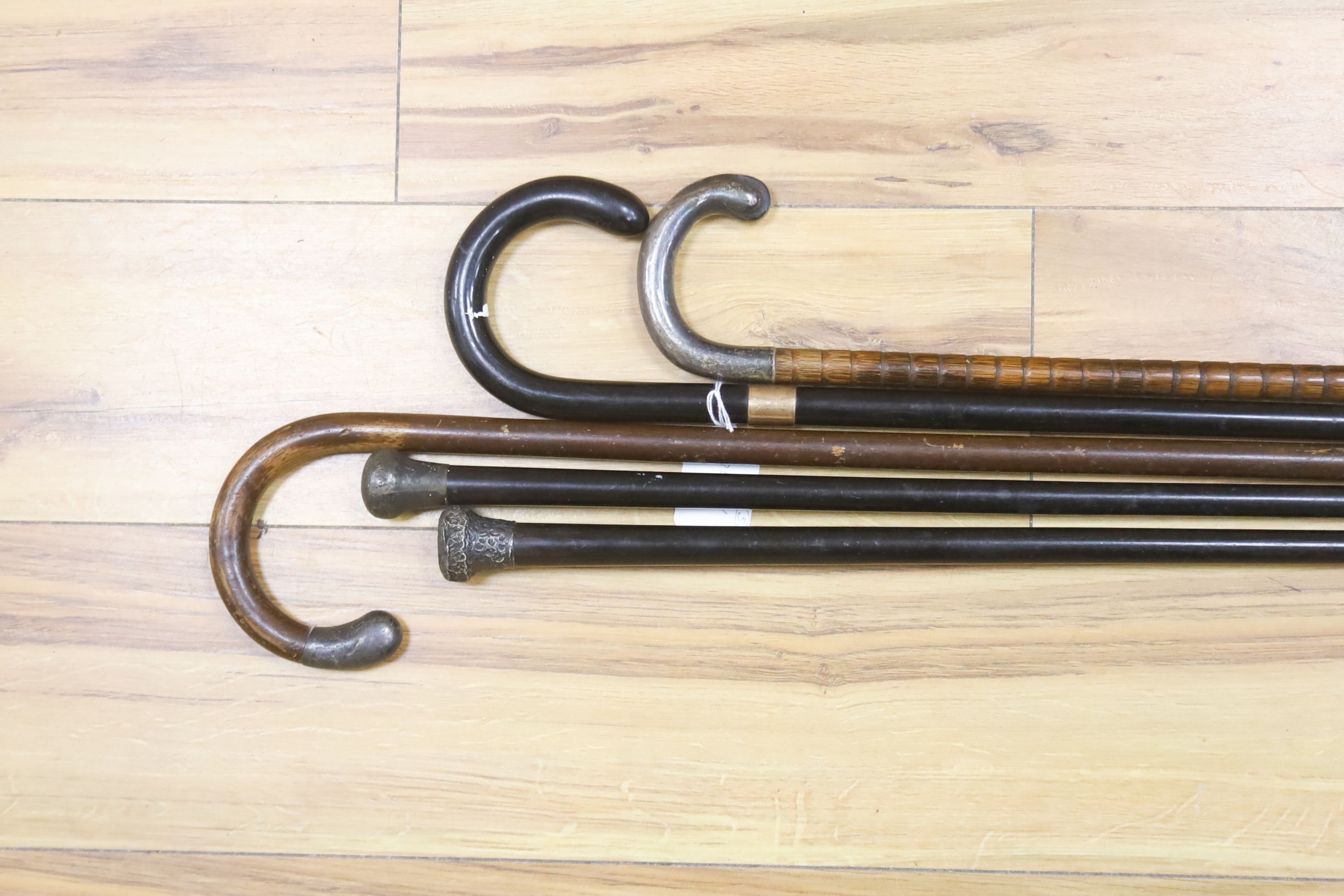 A 9ct gold mounted walking stick, three silver-topped sticks and another